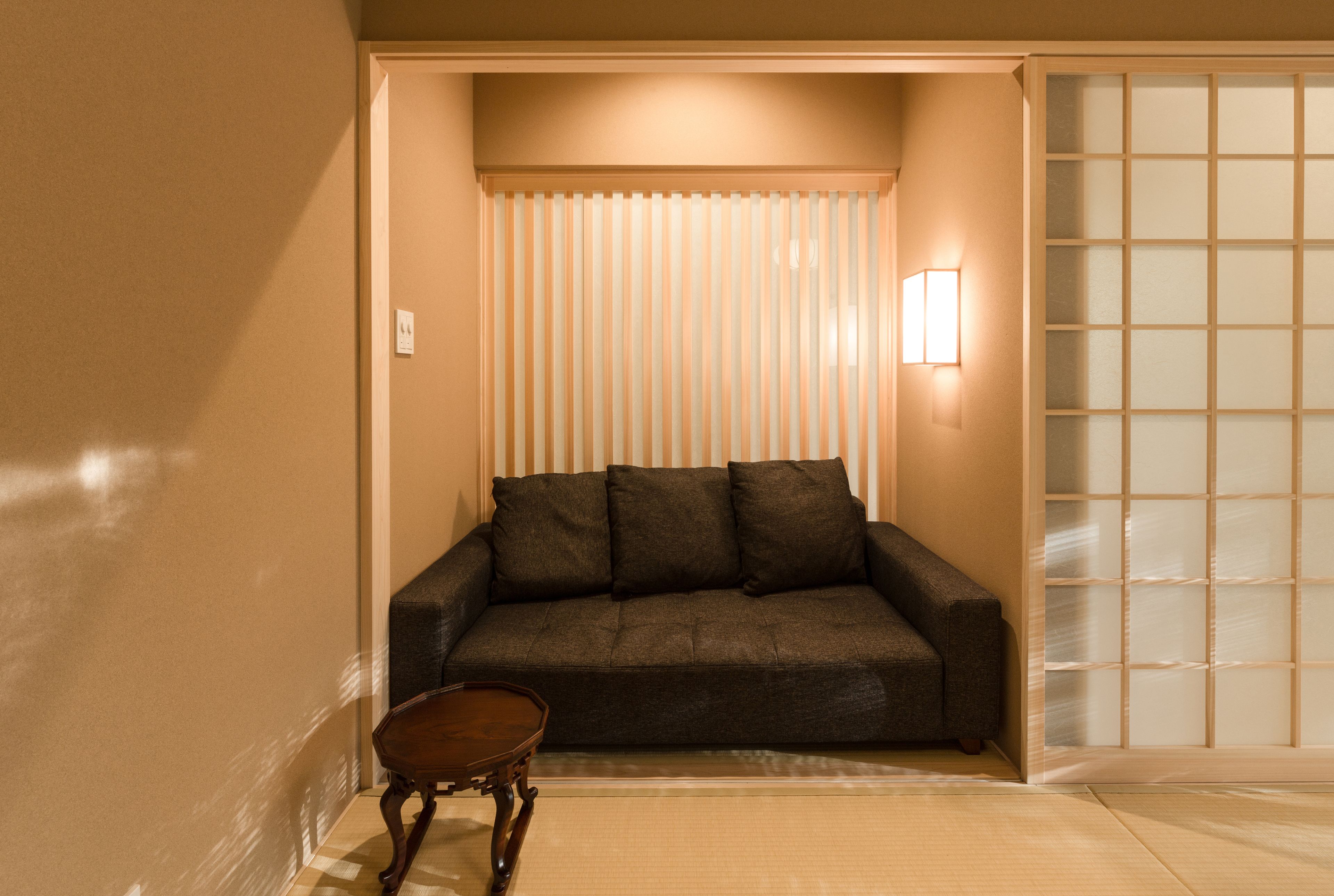Una habitación con un sofá marrón oscuro, una pequeña mesa de madera y un panel corredizo shoji.