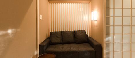 Una habitación con un sofá marrón oscuro, una pequeña mesa de madera y un panel corredizo shoji.