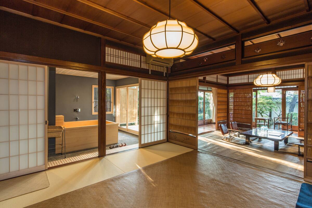 A traditional Japanese room with tatami flooring, sliding doors, and a low table with chairs.