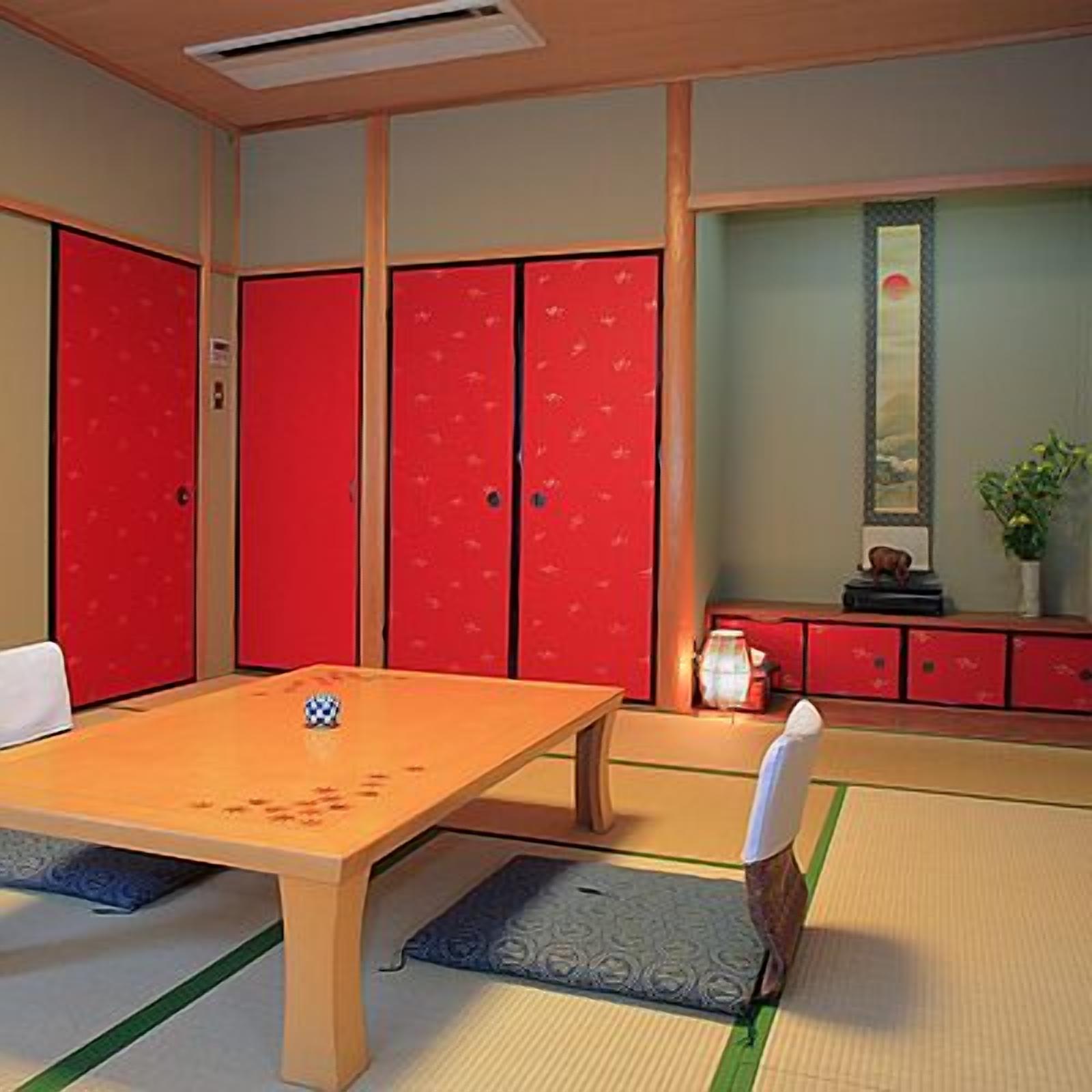 Una habitación con esterillas de tatami, una mesa baja, taquillas rojas y un pequeño armario con una planta.