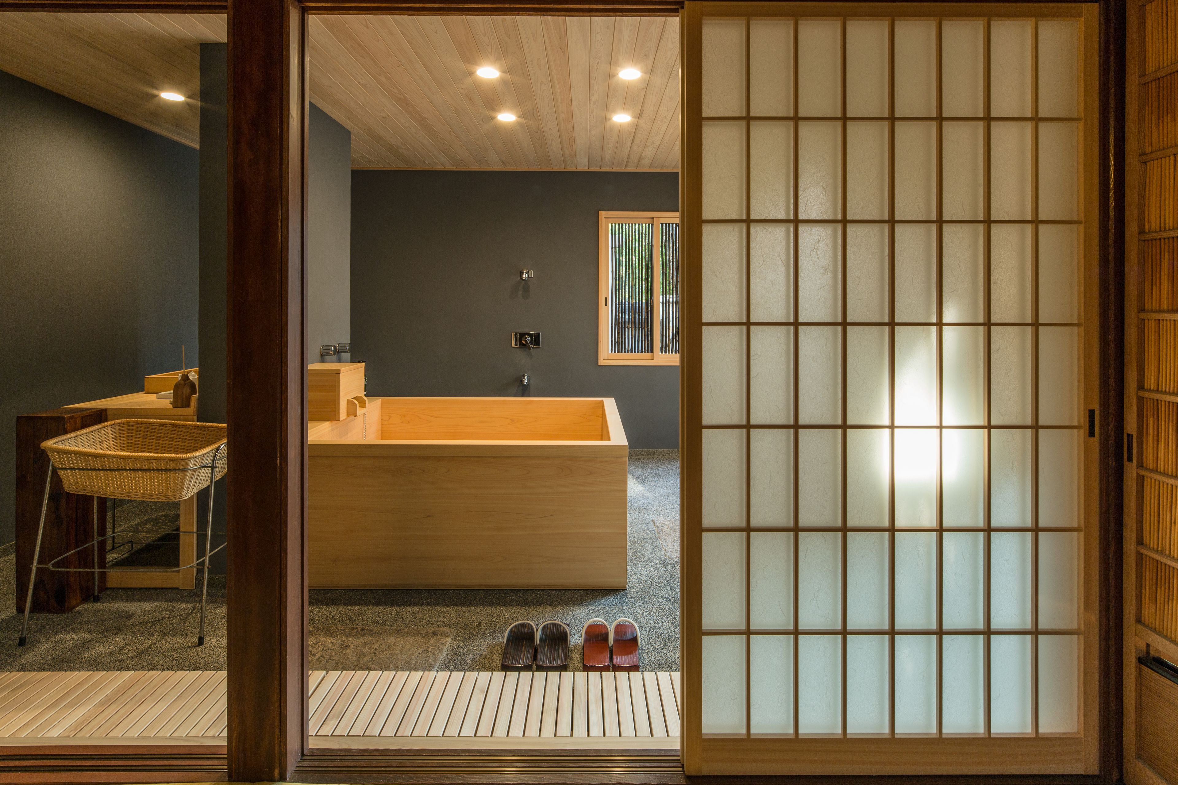 Um quarto tradicional japonês com uma banheira de madeira, piso de esteira de tatame e um painel deslizante shoji.