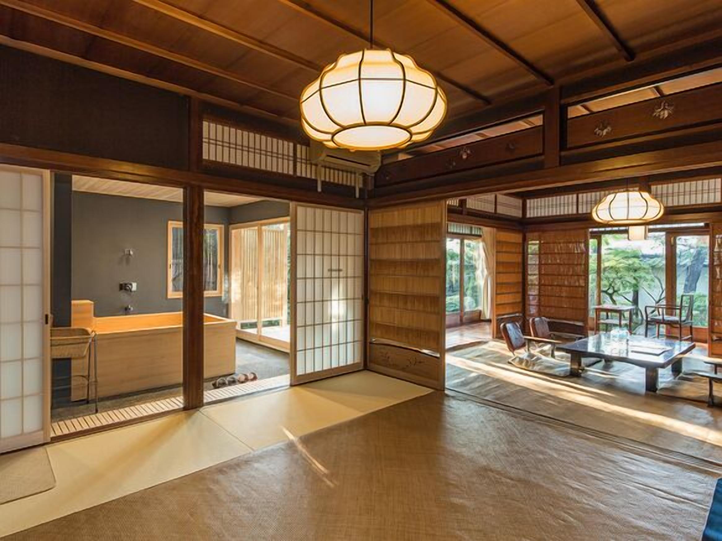 Un interior japonés tradicional con suelo de tatami, puertas correderas y una zona de comedor con una mesa baja y sillas.