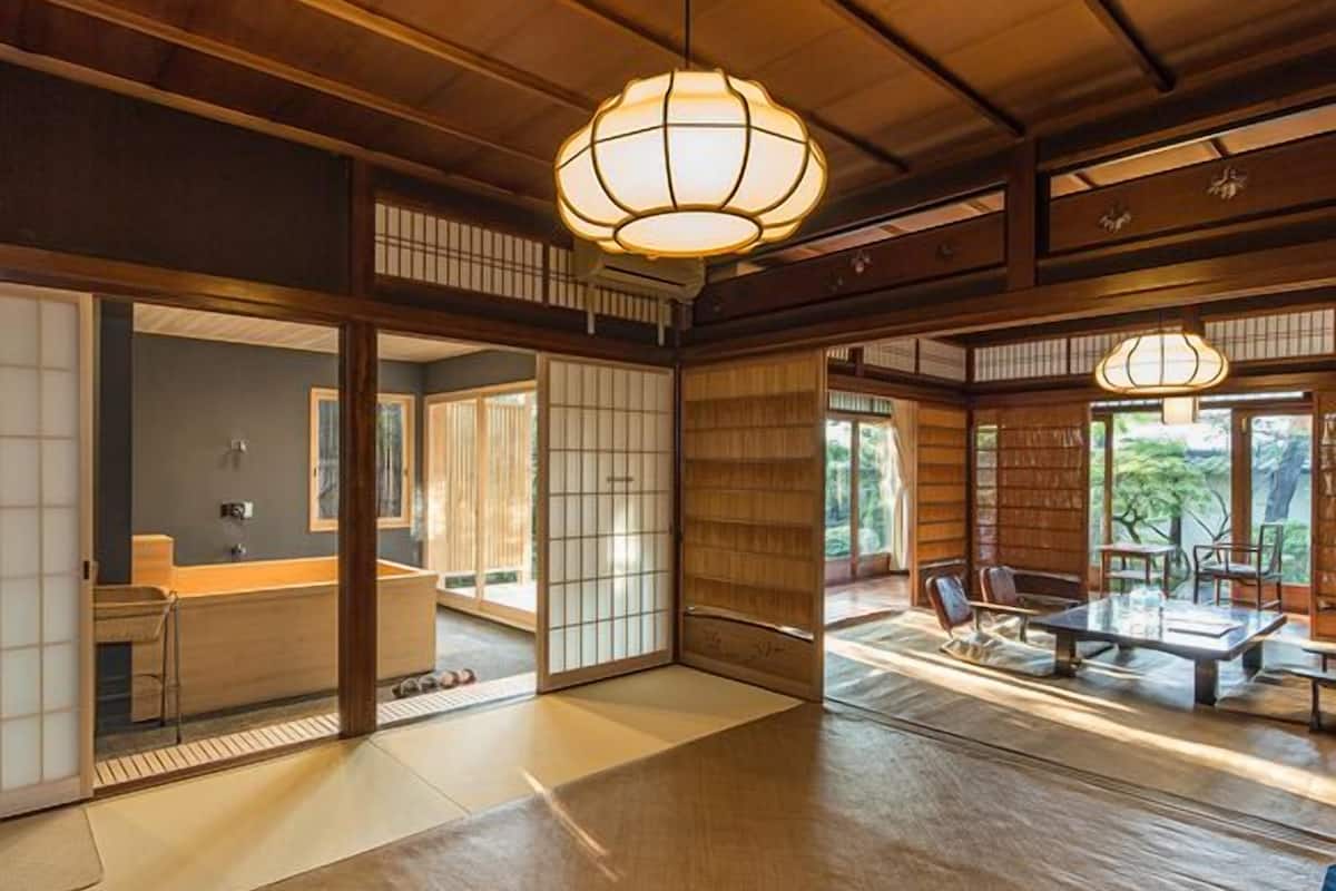 A traditional Japanese interior with tatami flooring, sliding doors, and a dining area with a low table and chairs.