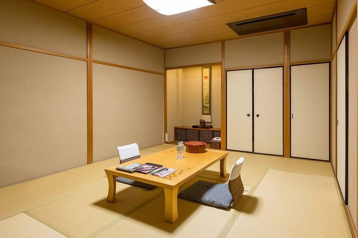 A traditional Japanese-style room with tatami flooring, a low wooden table, a white chair, and sliding doors.