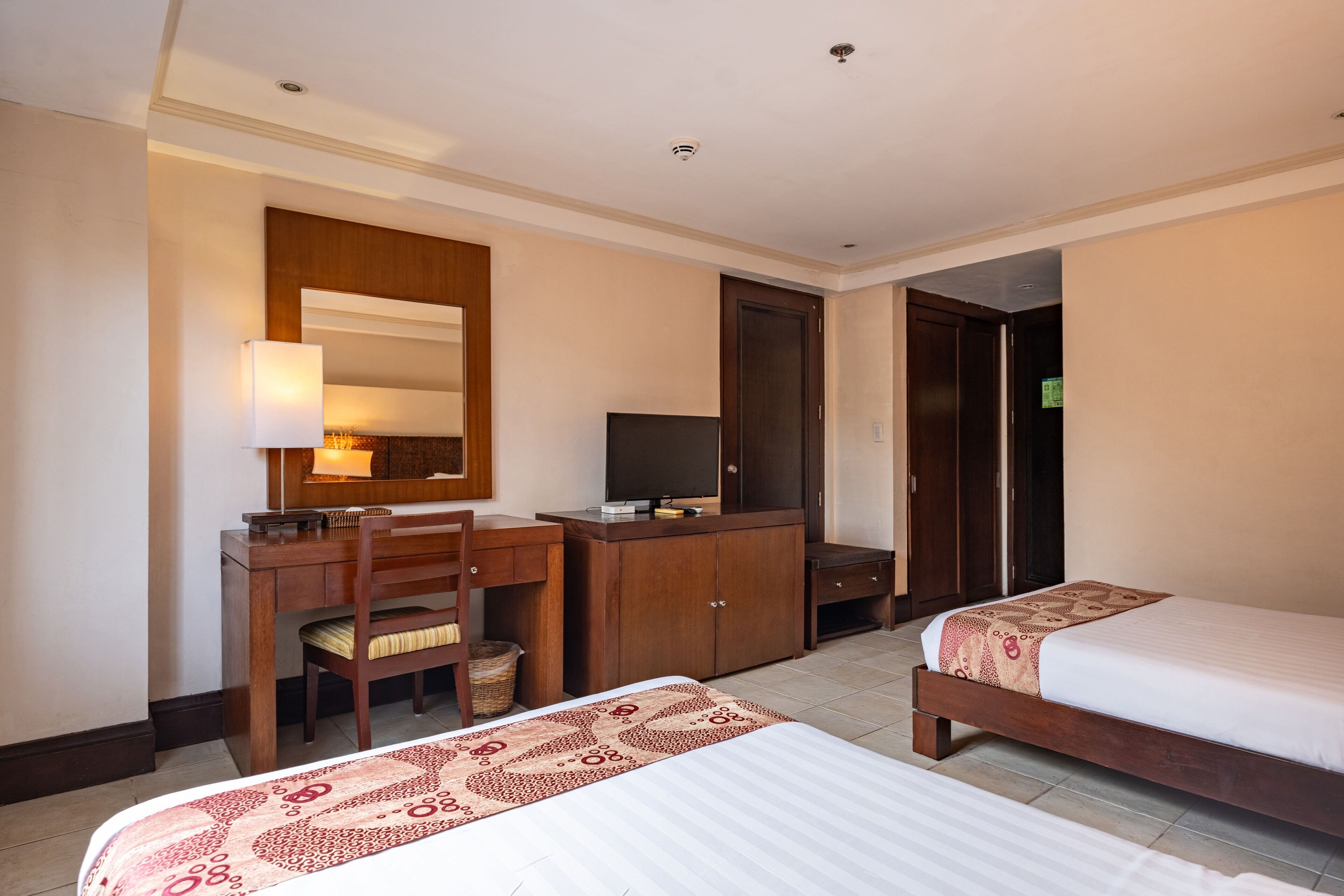 A hotel room with a bed, a desk with a chair, a television, and a wardrobe.