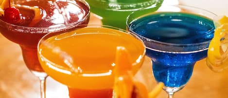 Une variété de cocktails colorés servis dans des verres à martini, posés sur une surface en bois.