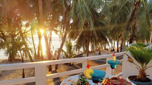 Une table garnie de nourriture et de boissons, une vue sur la plage et des palmiers.