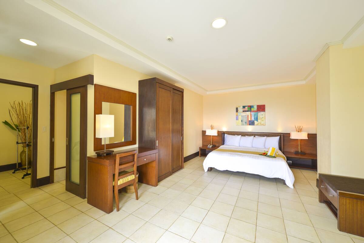 Een hotelkamer met een bed, bureau, stoel, kledingkast en bedlampjes.