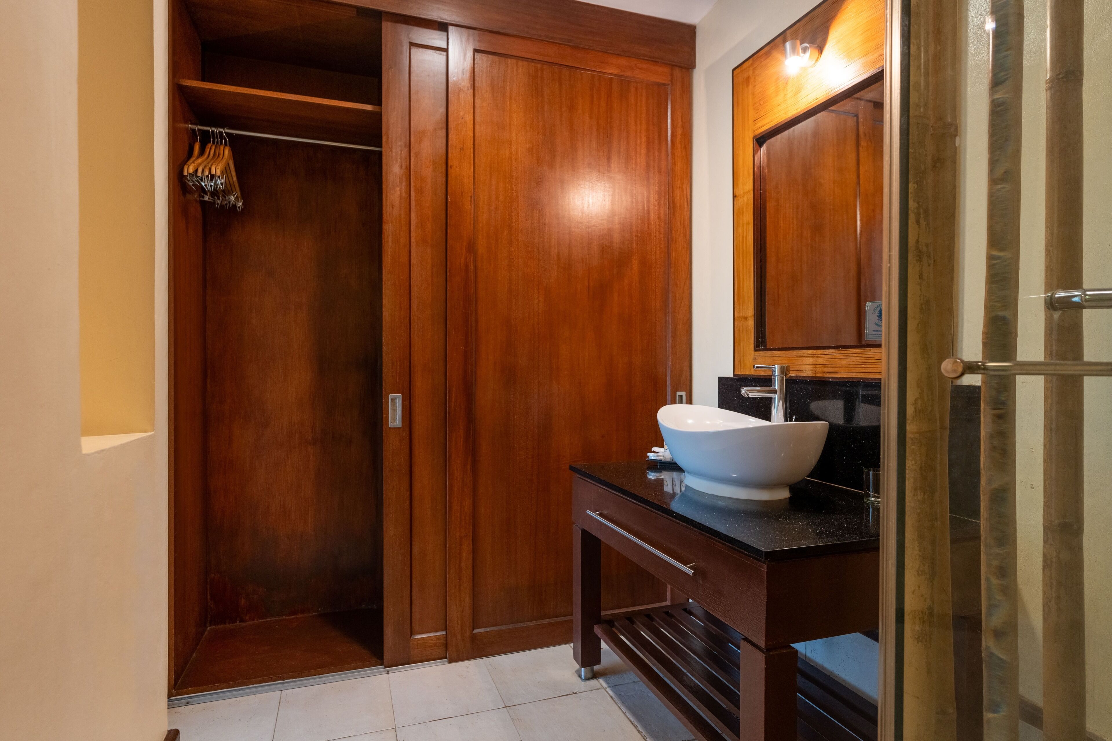 Un baño con tocador de madera, un espejo grande y un vestidor.