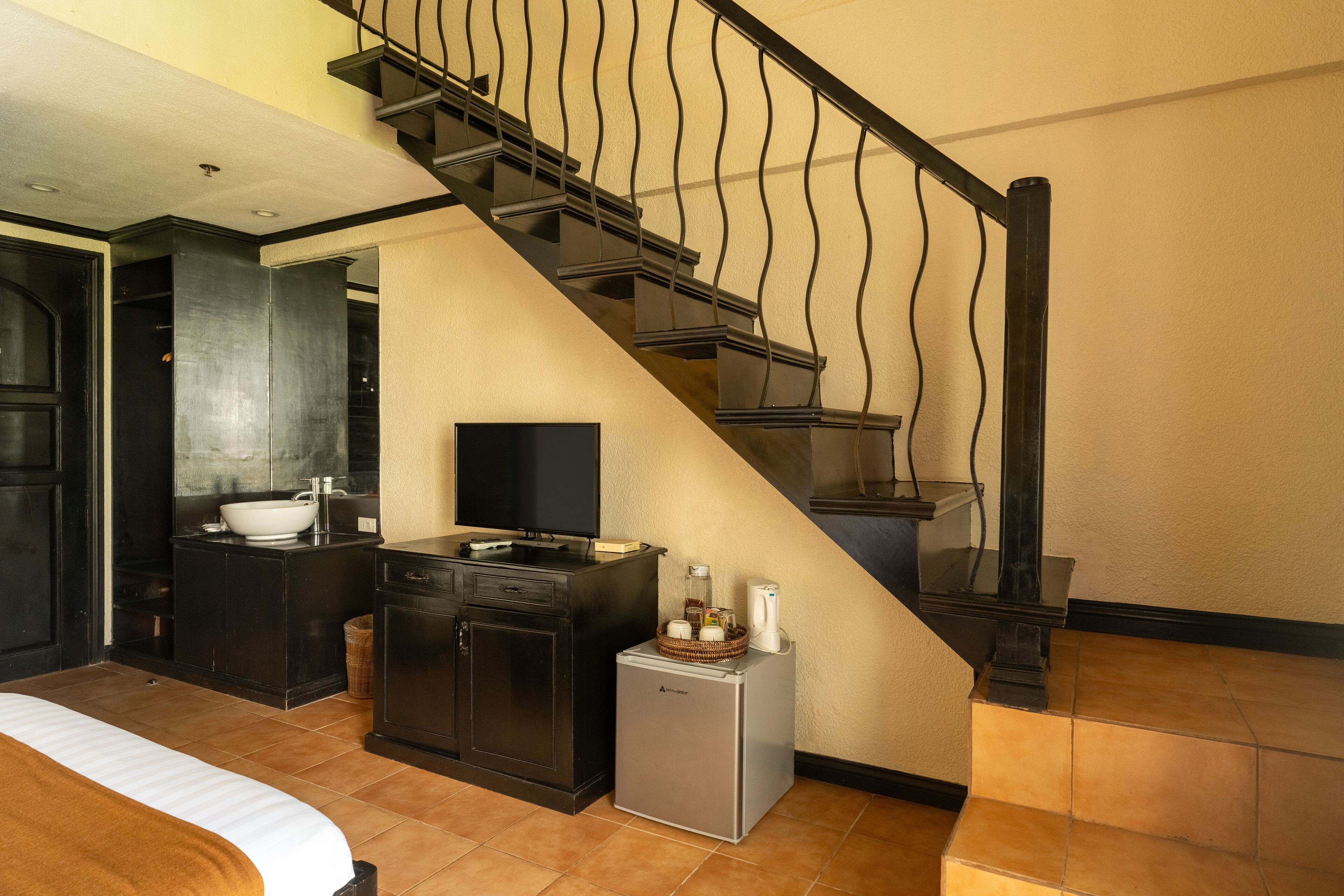 Une chambre d’hôtel comprenant un lit, une petite kitchenette, une salle de bain et un escalier.