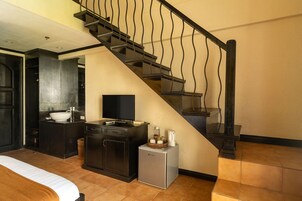 Una habitación de hotel con cama, una kitchenette pequeña, un baño y una escalera.