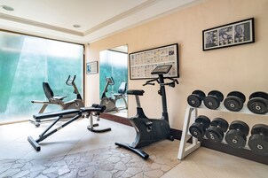 Un gimnasio con equipo de ejercicio, un estante para mancuernas en la pared y un espejo grande.