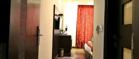 Een hotelgang met een bed, een bureau en een prullenbak.