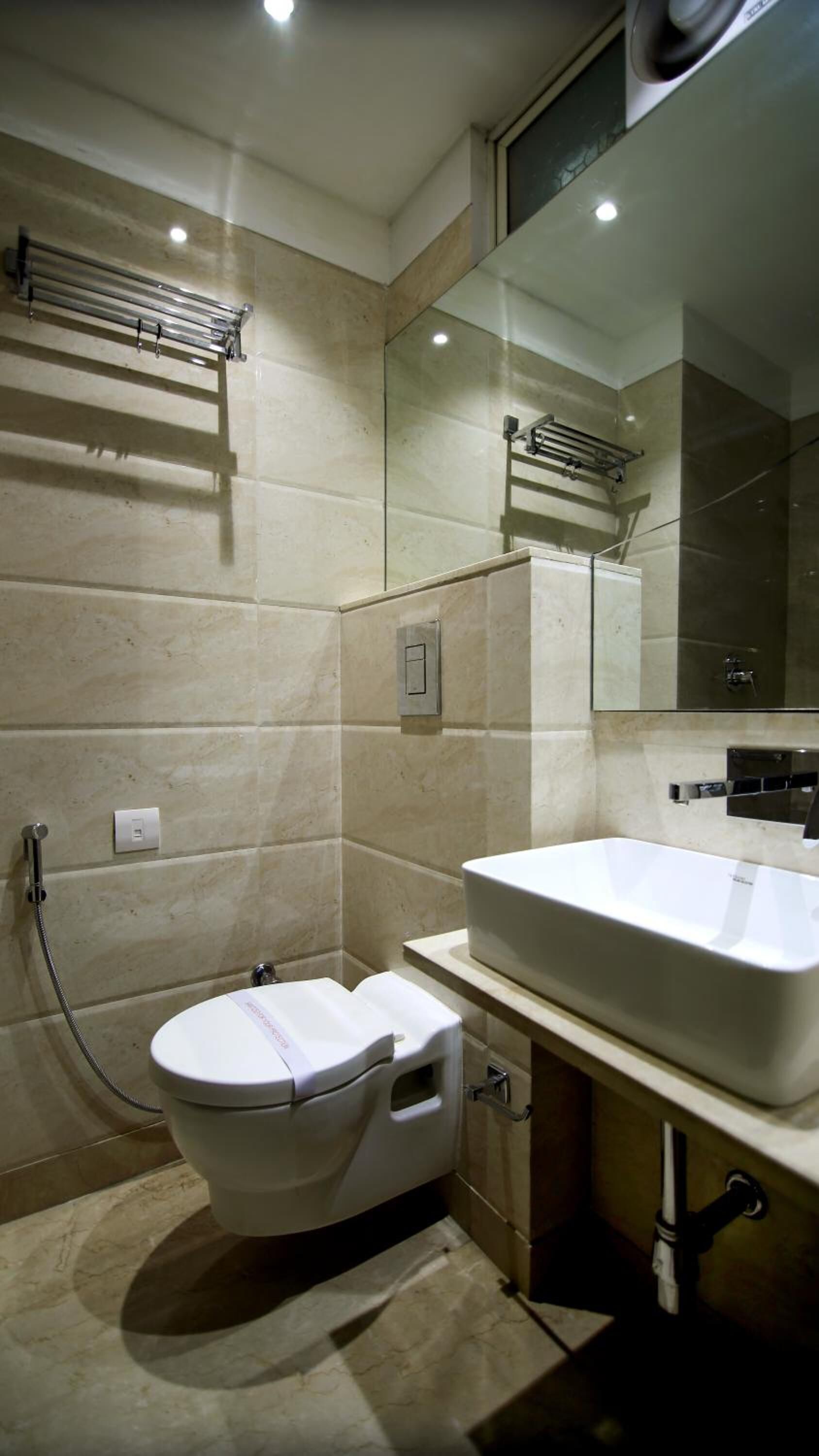 A modern bathroom with a white toilet, a large sink, and a mirror.