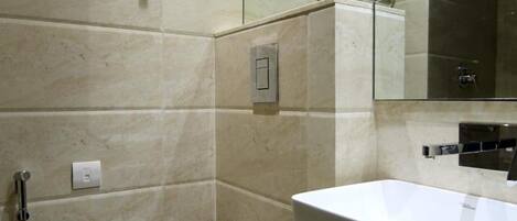 A modern bathroom with a white toilet, a large sink, and a mirror.