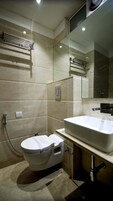 A modern bathroom with a white toilet, a large sink, and a mirror.