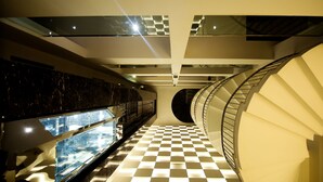 Ein modernes Interieur mit einem Schachbrettmuster-Boden, einer Glaskonstruktion und einer Wendeltreppe.