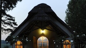 A thatched-roof structure with a red carpet leading to a central area with a chandelier. - Granny Mouse Country House & Spa (Lidgetton West)