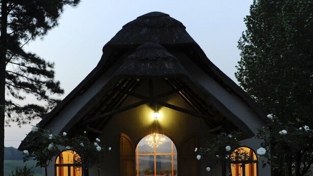A thatched-roof structure with a red carpet leading to a central area with a chandelier. - Granny Mouse Country House & Spa (Lidgetton West)