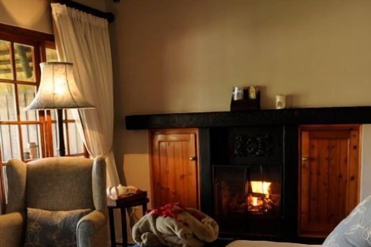 A cozy room with a fireplace, a sofa, a chair, and a bed with a blue runner.