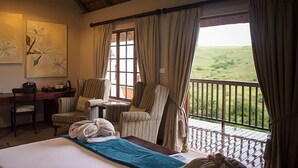 A bedroom with a bed, a desk, and two chairs. There is a balcony with a view of the countryside. - Granny Mouse Country House & Spa (Lidgetton West)