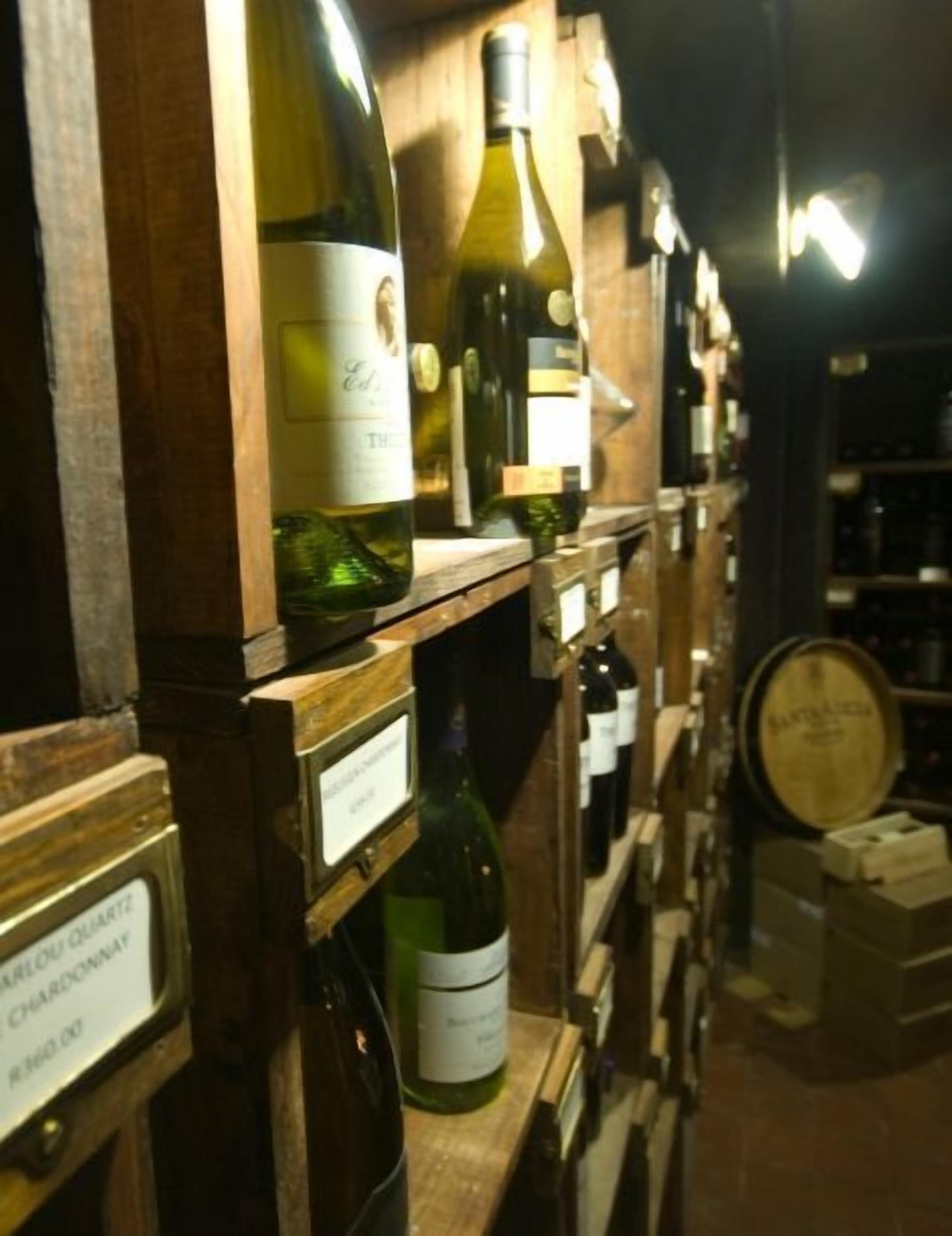 Una cantina vinicola con scaffali in legno che contengono diverse bottiglie di vino e una botte.