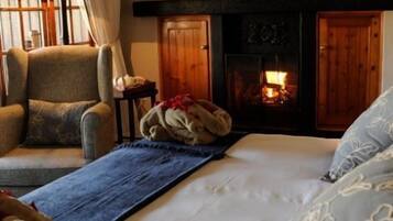 A cozy room with a fireplace, a sofa, and a bed with floral pillows.
