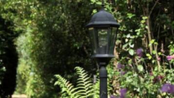 Un sendero en un jardín con un farol negro.