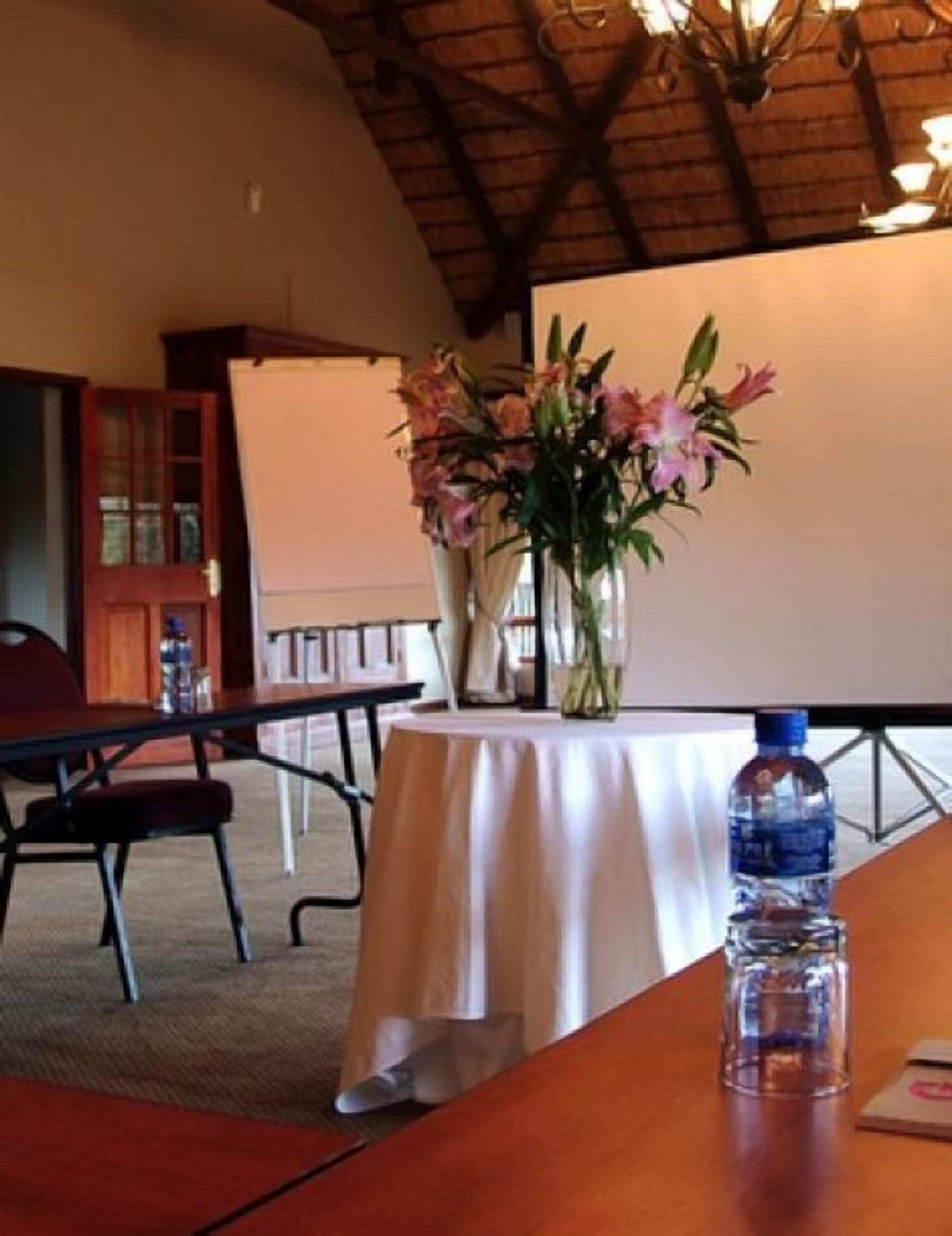 A conference room with a round table, a water bottle, and a vase with flowers.