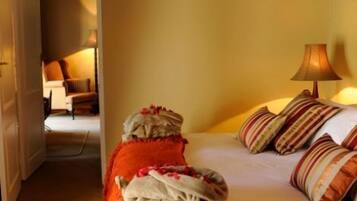 A hotel room with a bed, a nightstand, a lamp, and a view of another room.