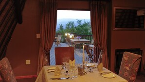A dining area with a table set for two, a view of the outdoors, and a fireplace. - Granny Mouse Country House & Spa (Lidgetton West)