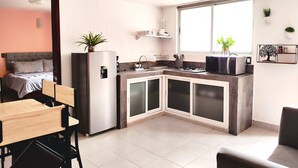 A compact kitchen with a refrigerator, stove, and microwave. - Hotel Jardines del Carmen (San Cristóbal de las Casas)