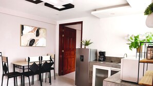 A modern kitchen with a dining area, featuring a refrigerator, coffee maker, and potted plants. - Hotel Jardines del Carmen (San Cristóbal de las Casas)
