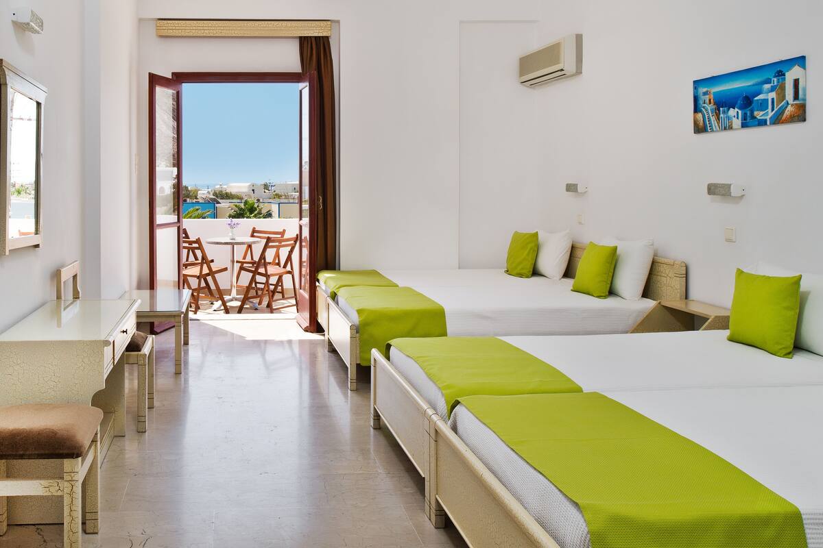 Ein Hotelzimmer mit zwei Betten, einem Esstisch und Meerblick.