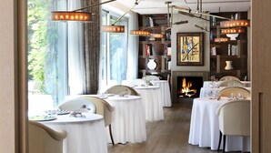 A dining area with round tables, chairs, a fireplace, and bookshelves. - ABaC Hotel Boutique 5 GL (Barcelona)