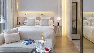 Een moderne hotelkamer met een groot bed, een bank en een kleintje tafeltje met een fles en glazen.
