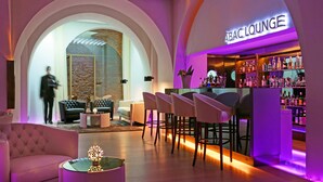 A bar/lounge area with a modern design, featuring a bar counter with a variety of bottles and a seating area with leather chairs and sofas. - ABaC Hotel Boutique 5 GL (Barcelona)
