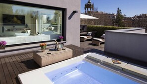 A modern outdoor terrace with a hot tub, lounge chairs, and a view of a historic building. - ABaC Hotel Boutique 5 GL (Barcelona)