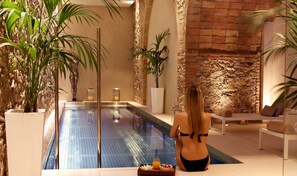 Un área de spa con piscina, asientos y plantas.