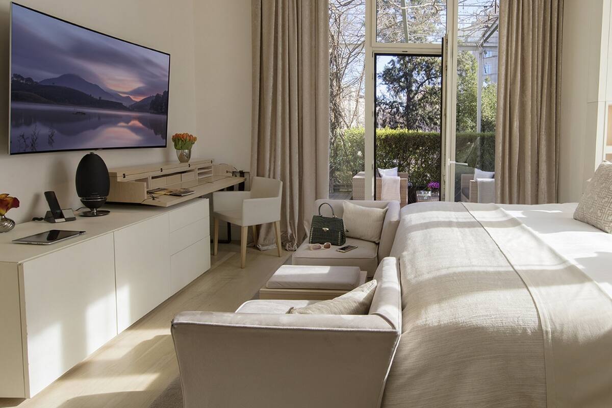 A modern hotel room with a large bed, a desk, and a TV.