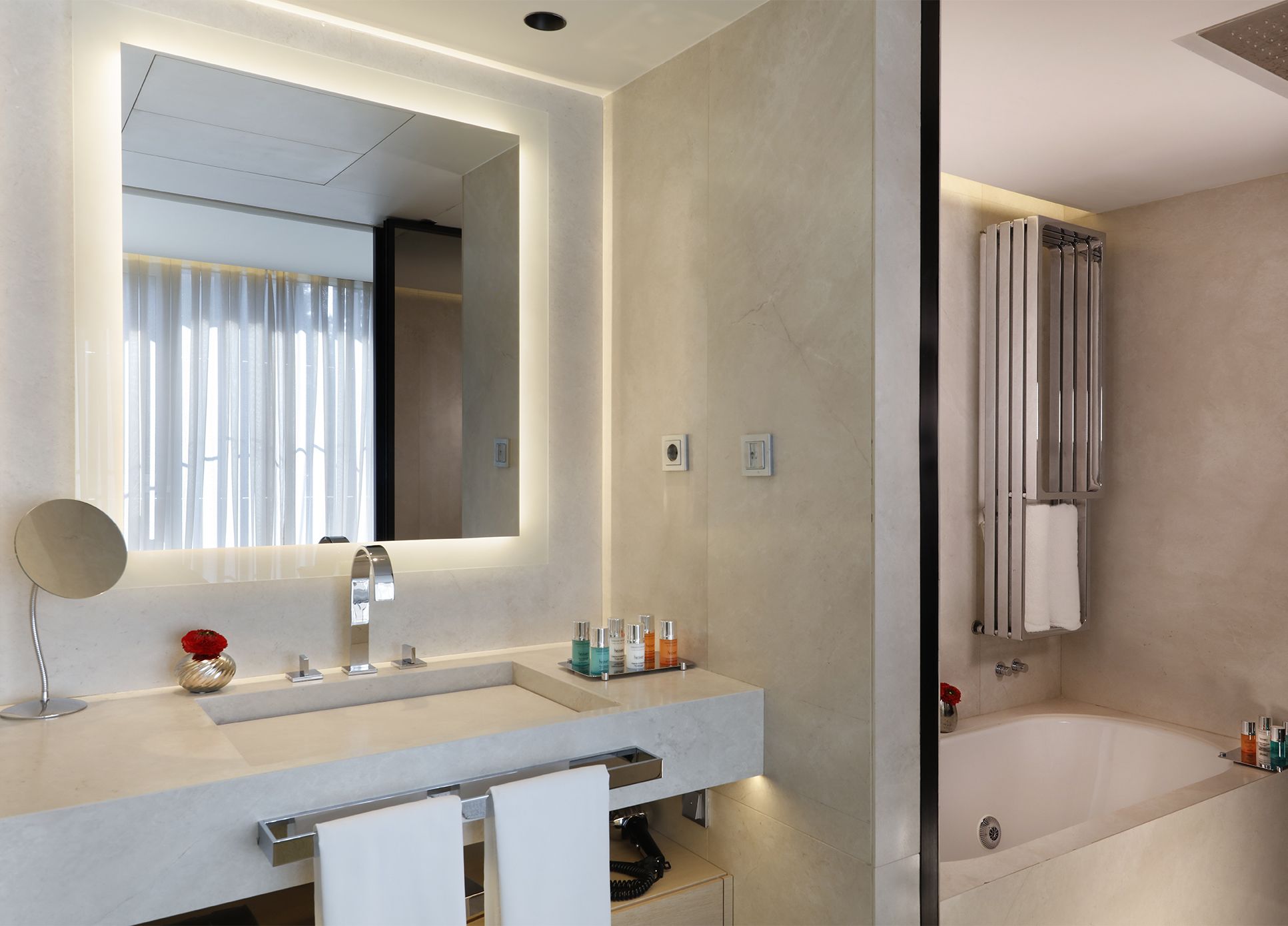 Un baño moderno con un espejo grande, lavamanos dobles, una bañera y zona de ducha.
