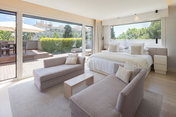 A modern bedroom with a large bed, two sofas, a small table, and a balcony with outdoor furniture. - ABaC Hotel Boutique 5 GL (Barcelona)