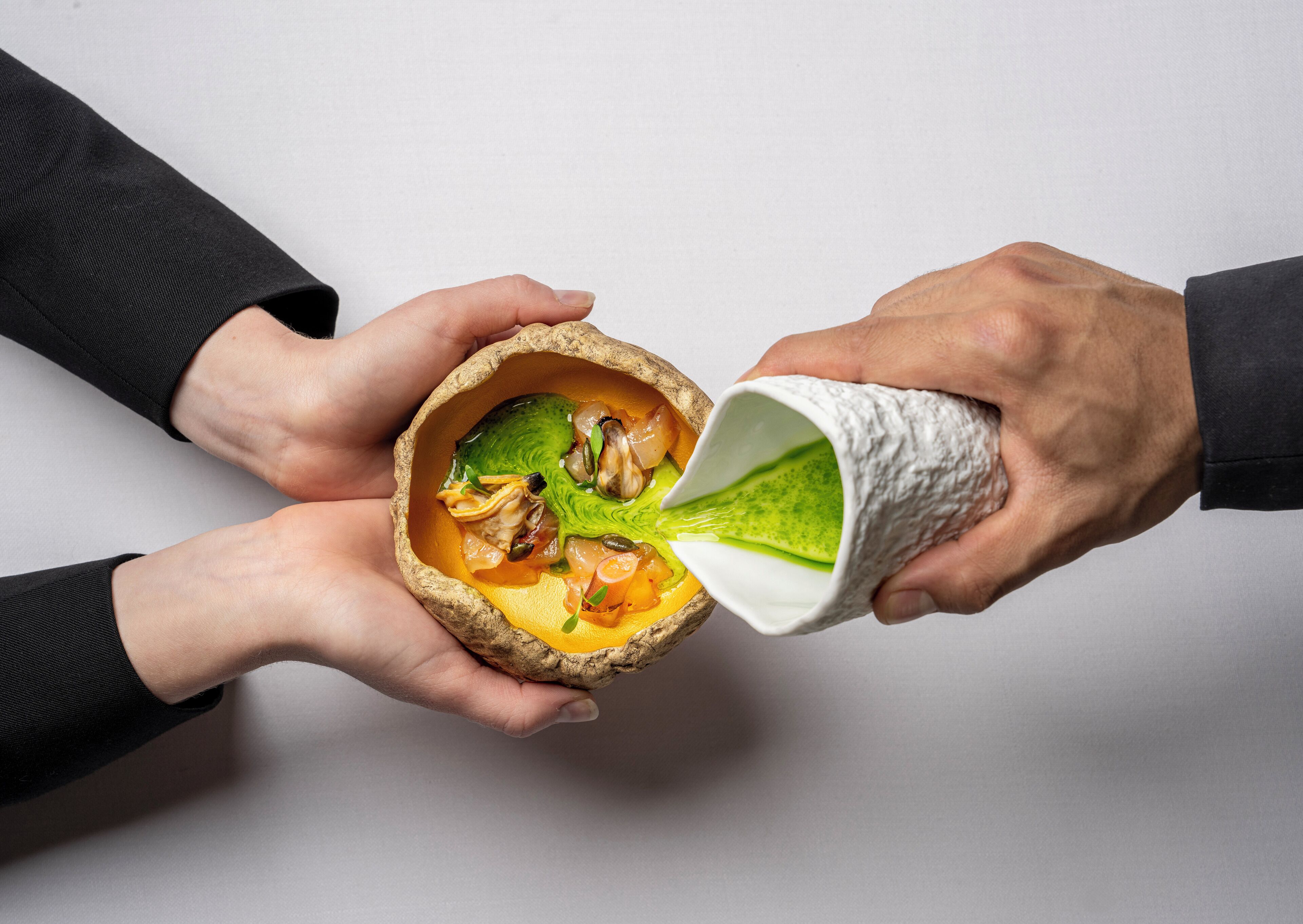 Two hands holding a bowl containing a dish with various ingredients.