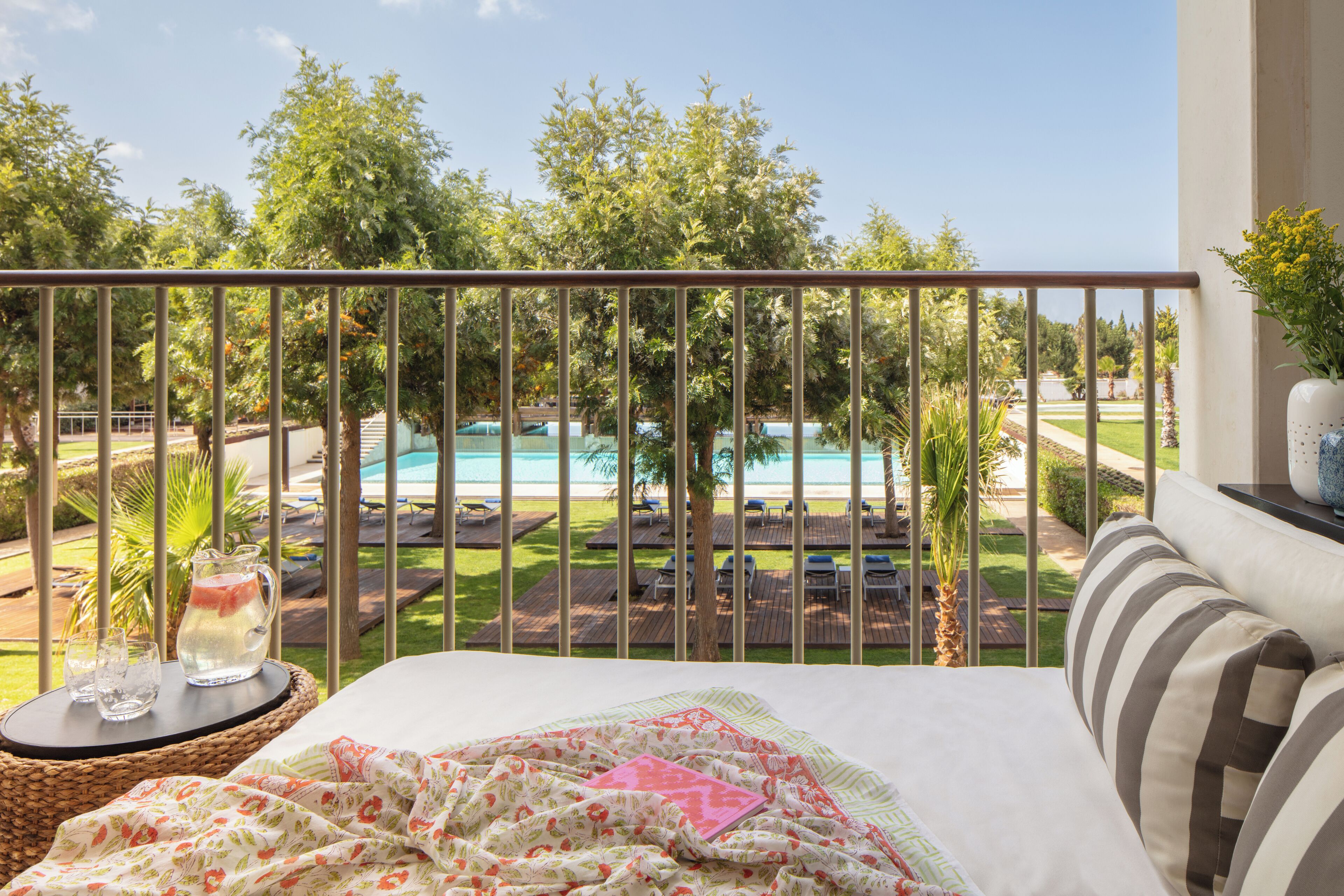 Un balcon avec un lit, une vue sur la piscine et des chaises longues.