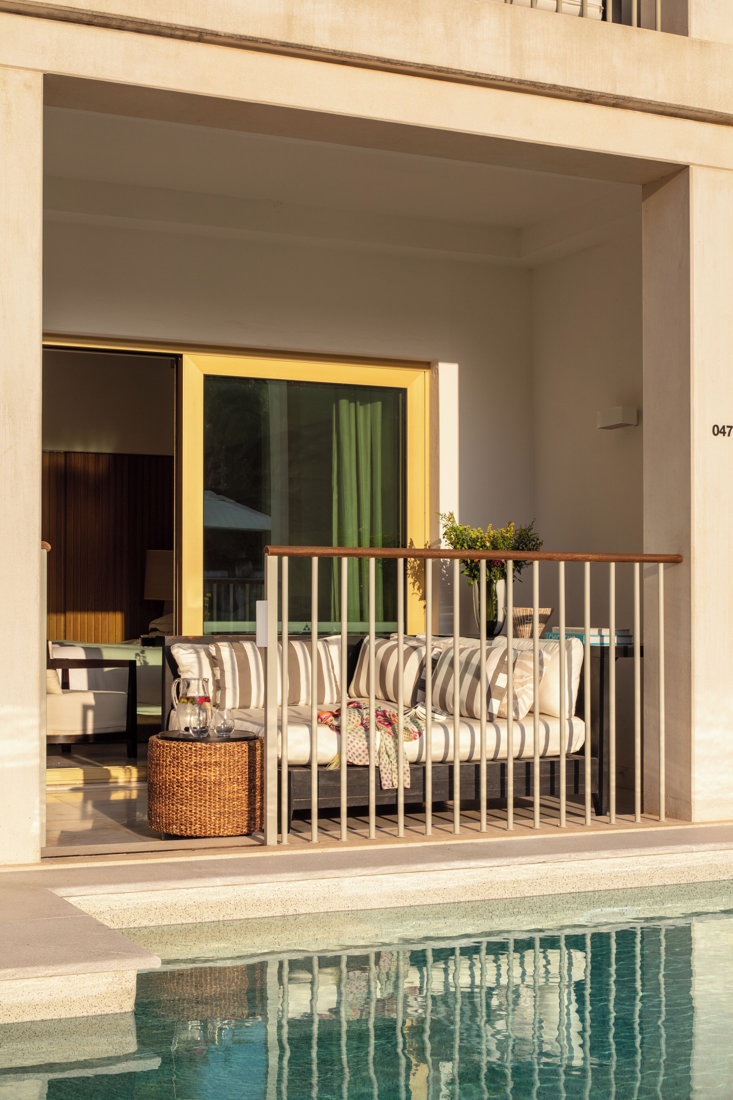 Un balcón con piscina, un sofá y una cesta de mimbre.