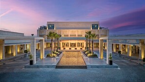 Un hotel moderno con un patio central, varios pisos y una fachada simétrica.