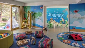Explore a vibrant playroom designed for kids, featuring a soft play area, ball pit, and engaging mural.