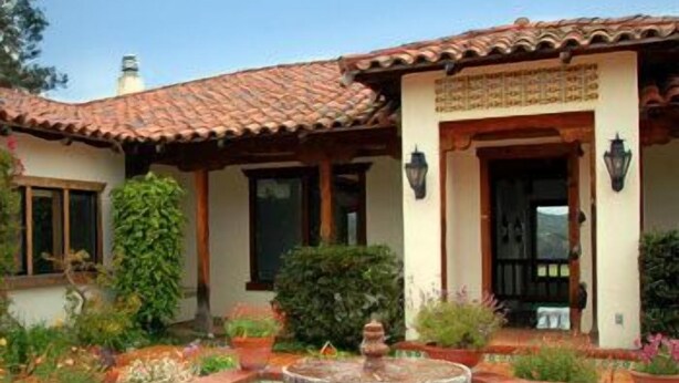 A courtyard with a tiled pool, potted plants, and a fountain.