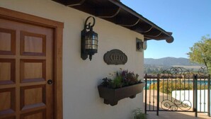 A building with a wooden door, a wall-mounted lantern, a sign with the name 'Cielo', and a planter with flowers.