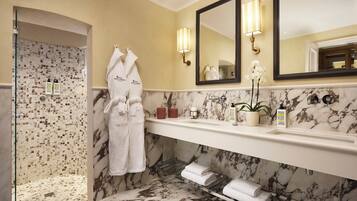 Un bagno con un mobile lavabo in marmo, cabina doccia in vetro e un ampio specchio illuminato da applique.